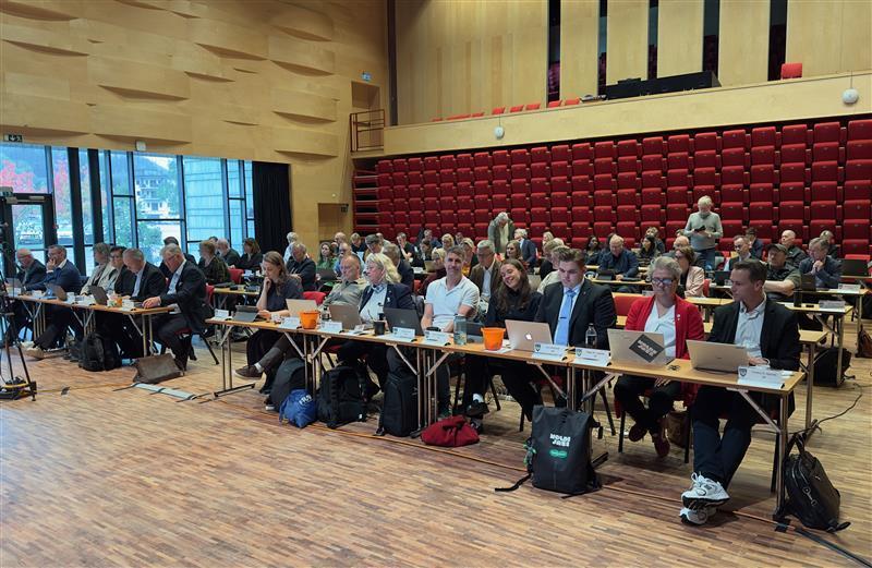 mange menneske som sitt i ein stor sal